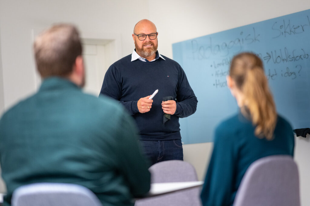 Michael Neigaard står ved en tavle og afholder kursus i Pædagogisk Sikkerhed®.